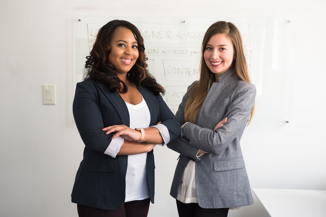 two-women-in-suits-standing-beside-wall-swi1dgrcshq
